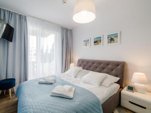 a bedroom with a large bed with two towels on it at Luxury Apartment Baltic Polanki Park in Kołobrzeg
