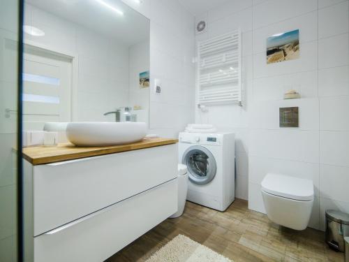 a white bathroom with a sink and a washing machine at Luxury Apartment Baltic Polanki Park in Kołobrzeg