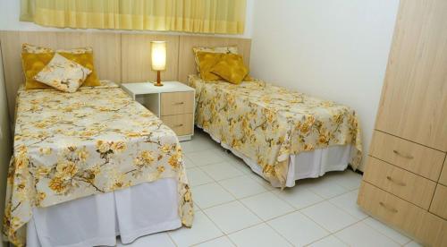 a bedroom with two beds and a lamp in it at Vila Dunas in Aquiraz
