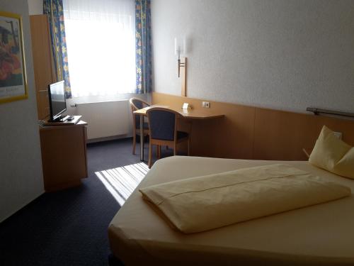 a hotel room with a bed and a desk and a window at Motel Am Highway in Althengstett