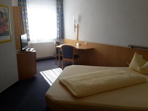 ein Hotelzimmer mit einem Bett, einem Schreibtisch und einem Fenster in der Unterkunft Motel Am Highway in Althengstett