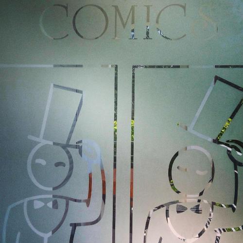 a store window with a company sign on the wall at Villa Comics in Villammare