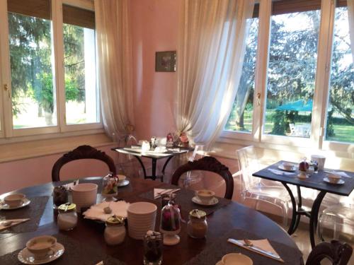 a dining room with tables and chairs and windows at Agriturismo Villa Dei Gelsi in Cotignola