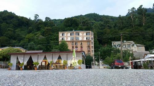 a building in a gravel parking lot next to a building at Hotel Kvariati Nugo in Kvariati