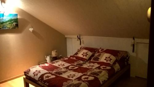 a bedroom with a bed with a red and white blanket at Les Nids de Mesanges Chambre d'hôtes in Selonnet