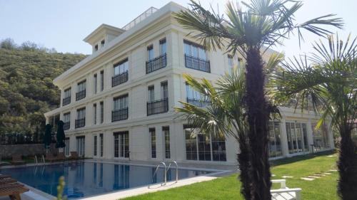 a large white building with a swimming pool and palm trees at The Escape Hotel in Agva