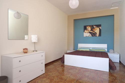 1 dormitorio con cama blanca y pared azul en La Tana del Lupo, en San Giovanni Gemini
