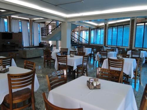 a dining room with white tables and wooden chairs at Hotel St. Daniel in Guarulhos