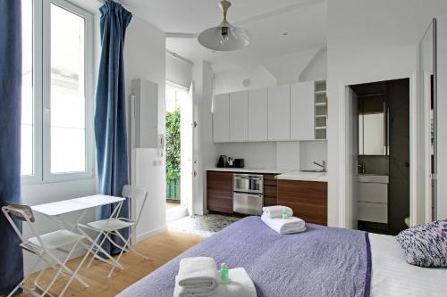 une chambre avec un lit et une table et une cuisine dans l'établissement Pick a Flat's Apartment in Montmartre - Rue des Martyrs studio, à Paris