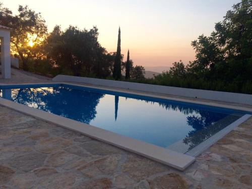 a swimming pool with a sunset in the background at B&B Casa Encantada in Boliqueime