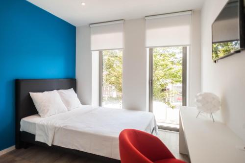 a bedroom with a white bed and a red chair at Ooostel2.be Leuven in Leuven