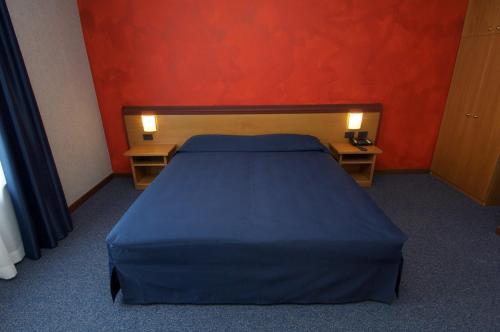 a bedroom with a blue bed and a red wall at Hotel Residence Ducale in Porto Mantovano