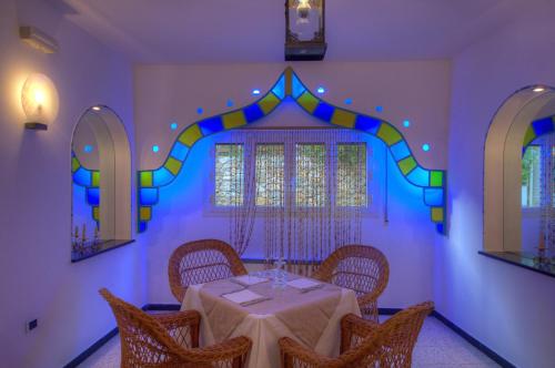a dining room with a table with chairs and mirrors at Hotel Arabesque in Varigotti