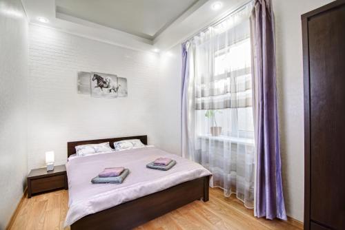a bedroom with a bed and a window with purple curtains at Premium Hostel in Lviv