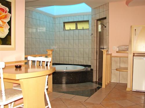 y baño con bañera, mesa y sillas. en Motel Monza (Adults Only), en Farroupilha