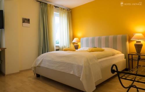 a bedroom with a bed with yellow walls and a window at Hotel 3 Könige in Aachen