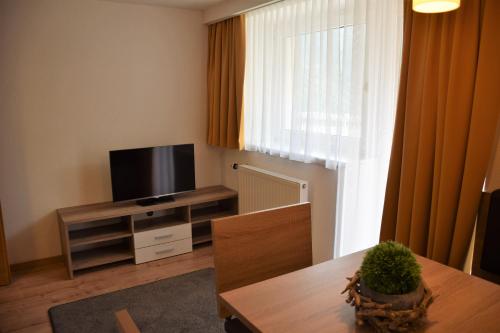 ein Wohnzimmer mit einem Flachbild-TV und einem Tisch in der Unterkunft La Mezza Luna in Kappl