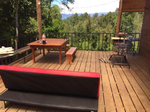 una terraza de madera con mesa y parrilla en Cabaña Lago Villarrica ideal 2 familias, en Villarrica