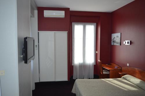 a red room with a bed and a window at Hotel de La Paix in Oloron-Sainte-Marie