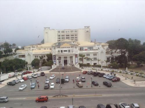 un gran edificio blanco con coches aparcados en un aparcamiento en De la Barra, Arriendos Vista Mar, en Viña del Mar