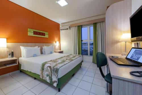 a hotel room with a bed and a desk with a computer at Sleep Inn Manaus in Manaus