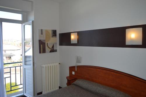 a bedroom with a bed and a sliding glass door at Hotel de La Paix in Oloron-Sainte-Marie
