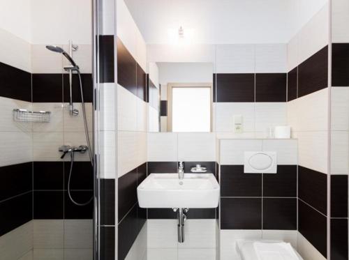 a black and white bathroom with a sink and a shower at Penzion Sokolská in Zlín