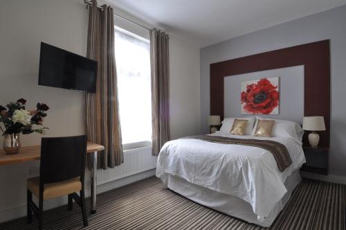 Dormitorio con cama, escritorio y TV en RBS Hotel en Rochester