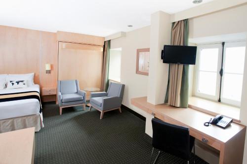 a hotel room with a bed and a desk and chairs at Hotel du Vieux Quebec in Quebec City
