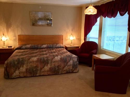 a bedroom with a large bed and a red chair at Western Budget Motel #1 Grande Prairie in Grande Prairie