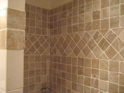 baño con paredes de azulejos marrones y ducha. en Maison d'Hôtes de l'Evêché, en Vaison-la-Romaine