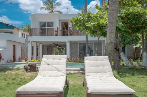 two white chairs in front of a house at Aaki Hotel in Las Peñitas