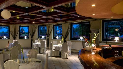 a restaurant with white tables and chairs and windows at Hotel Restauracja Tawerna Gliwice in Gliwice