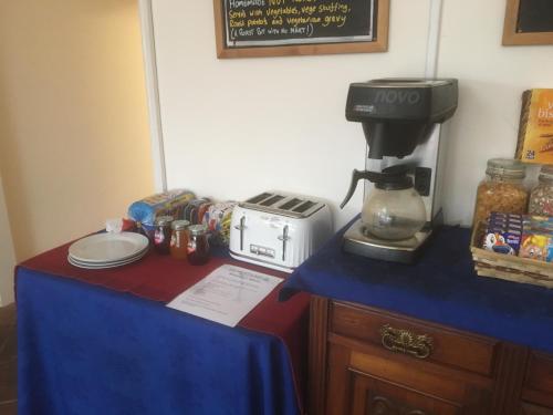 een tafel met een blauw tafelkleed en een koffiezetapparaat bij The White Lady in Worstead