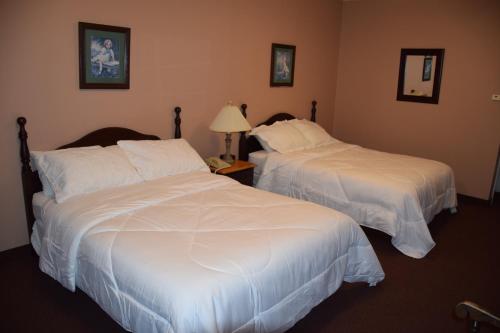 two beds in a hotel room with white sheets at Lynwood Inn in Baddeck