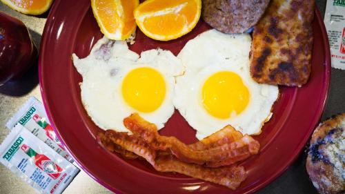 a red plate with eggs and bacon and toast at Quality Inn Perryton in Perryton
