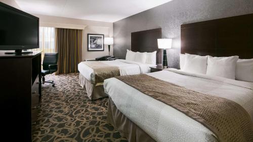 a hotel room with two beds and a flat screen tv at Best Western Ramkota Hotel Aberdeen in Aberdeen