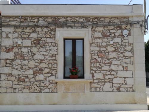 a window in a stone building with a flower pot at La casa di Bice in Cassibile