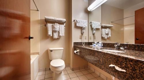 a bathroom with a toilet and a sink and a mirror at SureStay Plus by Best Western Edmond in Edmond