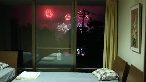 a room with two beds in front of a window at Atami Onsen Guest House Megumi 5 minutes walk from Atami Station in Atami