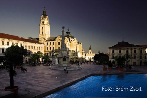 a large building with a clock tower in a courtyard at 35 Vendégház Pécs in Pécs