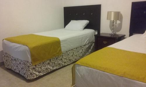 a bedroom with two beds and a table with a lamp at Room in Cancun Stadium in Cancún
