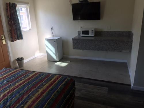 a bedroom with a bed and a microwave on the wall at Galleria Inn Montclair/Ontario in Montclair