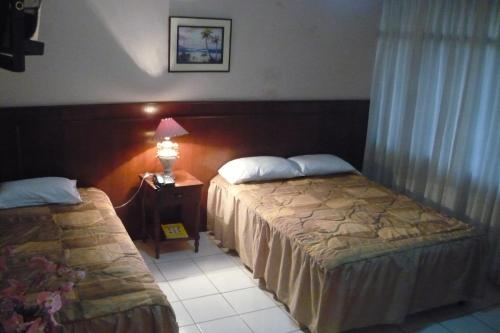 a hotel room with two beds and a table with a lamp at Hotel Princess in Ica