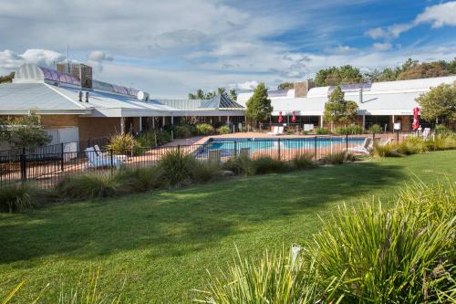 a house with a swimming pool and a yard at ibis Styles Canberra Eagle Hawk in Canberra