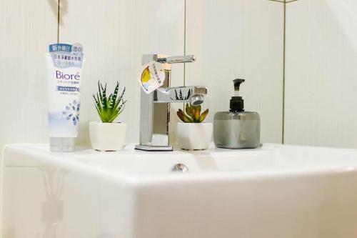 a white sink with plants and a bottle of soap at Okaeri in Anping