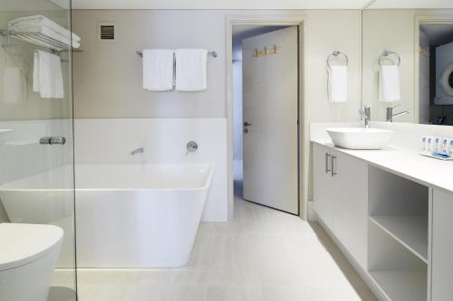 a white bathroom with two sinks and a toilet at Seashells Scarborough in Perth