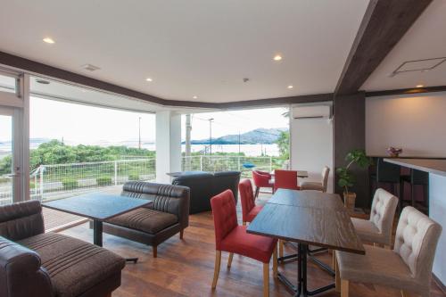 a living room with tables and chairs and a large window at Global Resort Miyajima View in Hatsukaichi
