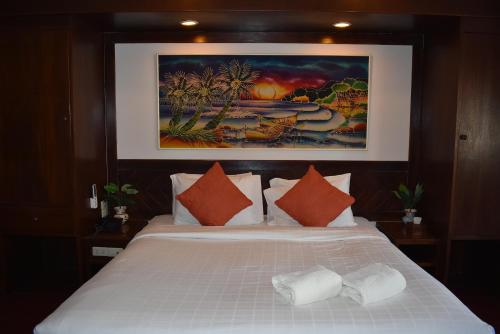 a bedroom with a large white bed with orange pillows at Karon Cafe Inn in Karon Beach