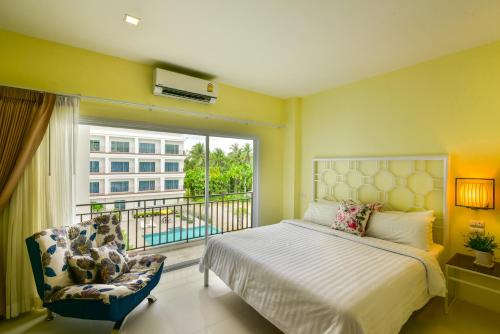 a bedroom with a bed and a window and a chair at Southgate Residence Hotel - SHA Certified in Chumphon